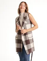 Chaleco tejido largo de la marca Absolutely Famous, con estampado a cuadros en tonos marrón, beige y blanco. Presenta cuello con solapa, abertura central, bolsillos aplicados en la parte delantera, pasadores en la cintura con lazo de ajuste y un tajo central en el ruedo trasero.