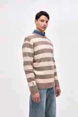 Buzo de punto con diseño de rayas horizontales en azul marino y beige, cuello redondo y puños acanalados. Presenta un pequeño bordado de estrella en la manga.