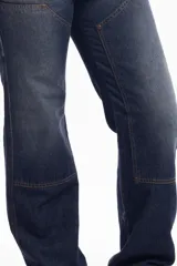 Pantalón de jean azul oscuro de corte recto, con refuerzos en las rodillas y bolsillos laterales. Diseño de estilo cargo con frente reforzado.