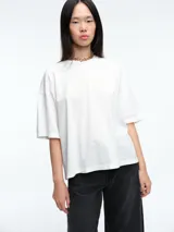 Remera de corte boxy y calce amplio, con cuello redondo y mangas cortas, de diseño minimalista y estructura relajada.