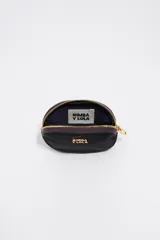 Monedero de forma ovalada marca Bimba y Lola, confeccionado en nylon color beige con detalles en verde oliva en el cierre y logo metálico dorado en el frente.