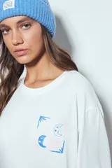 Remera de manga larga negra con cuello redondo y puños blancos visibles, presentando un estampado gráfico con motivos celestiales en el pecho.