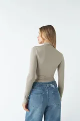 Body color visón con cuello tipo polera y mangas largas. Tiene frunces en los costados.