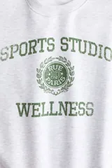 Buzo de cuello redondo con hombros caídos y diseño estampado en el frente. Presenta puños y bajo acanalados, con interior cepillado suave.