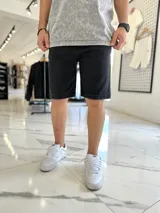 Bermuda de jean color negro, de corte clásico y largo por encima de las rodillas.