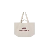 Bolso tipo tote bag de lona color beige, con doble juego de asas (cortas y largas), bolsillos laterales y el logo de la marca estampado en color marrón en el frente.