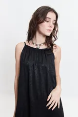 Vestido largo de silueta amplia y fluida, con breteles finos y escote redondeado. Presenta un diseño estampado con motivos geométricos en tonos bordó, beige y gris.