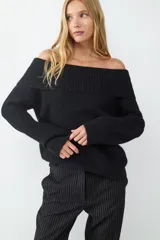 Sweater de punto negro con diseño off-shoulder, cuello amplio con textura acanalada, mangas largas y calce relajado.