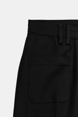 Pantalón de tiro alto con diseño flare, confeccionado en tela de color negro. Presenta cinco bolsillos, cintura con trabillas y cierre frontal con cremallera y botón.