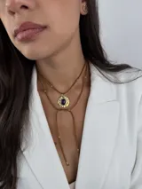 Colgante tipo choker con cordón de cuero marrón y dije metálico en forma de espiral dorada. El diseño incluye detalles de pequeñas cuentas metálicas a lo largo del cordón.