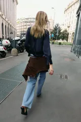 Camisa de cuello solapa y manga larga, confeccionada en tejido satinado azul marino. Presenta cierre frontal con botones forrados a tono y puños rectos.