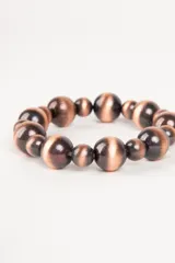 Pulsera elástica con cuentas redondas de diferentes tamaños en color cobre con efecto ojo de gato.