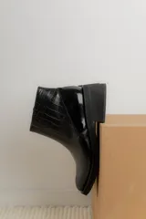 Bota corta de cuero marrón con panel trasero de gamuza en tono más oscuro, suela de goma negra y taco cuadrado bajo.