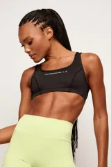 Top deportivo negro de alto rendimiento, con tirantes medianos, espalda baja y diseño con bolsillos internos para copas removibles.