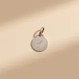 Dije circular de plata 925 con acabado satinado y letra grabada en el centro.