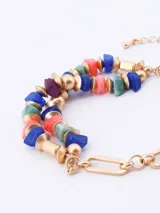 Pulsera elástica con cuentas de piedra irregulares en tonos azul, verde, rosa y morado, alternadas con cuentas doradas.
