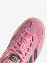 Championes Adidas Gazelle Indoor color rosa con las tres tiras laterales en negro y detalles en violeta.