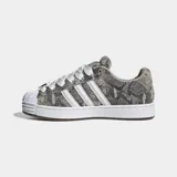 Championes Adidas Superstar ST de estilo skate, con exterior estampado en animal print de serpiente en tonos grises y tostados, las icónicas tres tiras blancas en los laterales y la clásica puntera de concha de goma blanca. Cuentan con cordones anchos blancos, lengüeta acolchada y suela chunky blanca con detalles marrones.