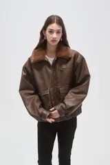 Campera de eco-cuero color marrón con cuello de piel sintética, cierre frontal, bolsillos frontales con solapa y puños y cintura elásticos.