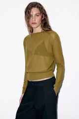 Jersey de punto fino con cuello redondo y manga larga con puños elásticos. Presenta un diseño minimalista con costuras visibles en los hombros.