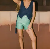 Shorts de cuero color coral, tiro alto, con bolsillos laterales y cierre frontal con botón.