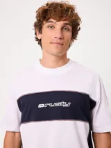 Remera holgada Rusty de diseño combinado en blanco y azul marino, con cuello redondo ancho, mangas cortas y detalle de ribetes oscuros a contratono. Cuenta con el logotipo de la marca estampado en el pecho.