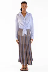 Camisa de manga larga color celeste, confeccionada en algodón, con cuello clásico, cierre frontal de botones y diseño cruzado con lazo para anudar en la cintura.