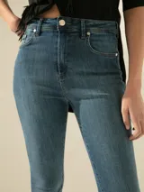 Jeans chupín de tiro medio-alto confeccionados en denim de algodón elastizado, con lavado medio y desgastes sutiles.