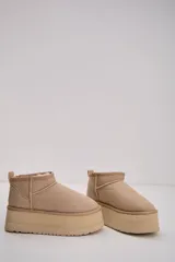 Bota corta tipo botineta en color beige, con diseño de caña baja y plataforma gruesa de goma al tono. Presenta costuras reforzadas y tirador en la parte posterior.