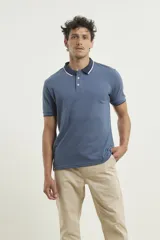 Chomba de piqué azul con cuello clásico, mangas cortas y corte recto. El cuello y los puños tienen detalles a contratono en azul marino y blanco.