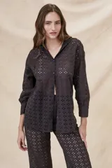 Camisa negra de algodón con bordado calado, corte oversize, cuello clásico, cierre frontal con botones y mangas largas con puños abotonados.