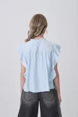 Blusa celeste de viscosa con diseño holgado, cuello a la base con detalle de volados, mangas cortas con volados y detalle de punto smock en el pecho.
