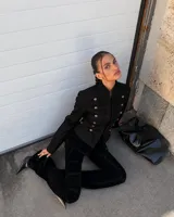 Blazer negro de estilo militar, con cuello mao, detalles de pasamanería bordada y doble botonadura frontal con botones dorados.