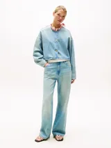 Campera de denim rígido en mezcla de algodón y lyocell, color celeste lavado. Presenta un corte cropped y oversize, sin cuello, con cierre frontal de tres botones dorados cepillados y hombros caídos.