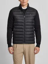 Chaleco acolchado negro Tommy Hilfiger, con cuello alto, cierre de cremallera, bolsillos laterales y logo bordado en el pecho.