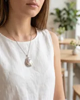 Collar de cadena fina con dije de acero en forma de mariquita que funciona como camafeo, permitiendo abrirlo para guardar una fotografía.