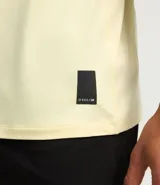 Remera deportiva de hombre con tecnología dry fit, cuello redondo y manga corta. Presenta un diseño liso en color beige con una pequeña etiqueta decorativa en el dobladillo.
