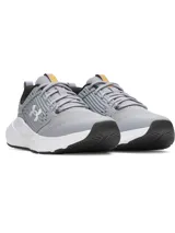 Championes de entrenamiento Under Armour modelo Charged Commit TR 4, color gris con detalles en blanco y negro. Presentan una parte superior de malla transpirable con refuerzos laterales texturizados y el logo de la marca en el costado. Cuentan con mediasuela Charged Cushioning para amortiguación y suela de goma con ranuras de flexión.