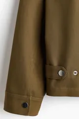 Sobrecamisa boxy de algodón, color verde militar, con cuello inglés, tapeta con botones a presión y bolsillos superiores con solapa.
