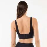 Top de bikini negro con escote en V pronunciado y aro metálico dorado en el centro.