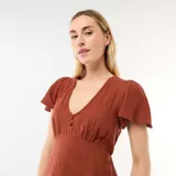 Vestido corto marrón con escote en V, mangas cortas estilo mariposa y detalle de botones frontales. Presenta un corte ajustado bajo el busto y falda ligeramente acampanada.