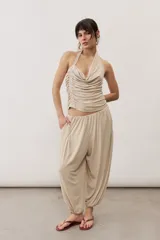 Pantalón de corte holgado estilo harén, color beige, con cintura elástica fruncida y puños elásticos en los tobillos. Cuenta con bolsillos laterales.