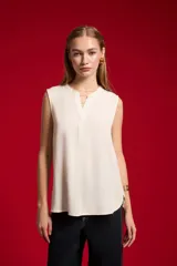 Blusa evasé de viscosa color blanco, sin mangas, con cuello a la base y escote en V con cartera frontal.