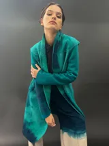 Tapado largo gris de lana merino con bolsillos laterales y corte particular en los hombros.