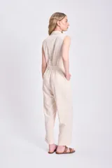 Mono largo color crudo de lino, con cuello en V, sin mangas, corte a la cintura con botón y pantalón de corte recto.