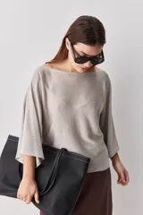 Sweater de punto liviano negro, con escote bote y mangas amplias de largo tres cuartos que aportan una silueta relajada y fluida.