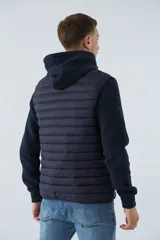 Chaleco puffer verde oliva con cierre frontal y bolsillos laterales con cierre. Interior forrado en color naranja.