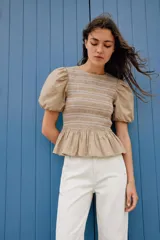Top color beige con cuerpo de nido de abeja elástico con bordados a contraste, mangas cortas abullonadas y detalle de volante en el bajo. Cuenta con cierre en la espalda con cremallera oculta.
