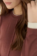 Remera color beige de mangas largas con cuello redondo y puños blancos en contraste.