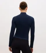 Campera deportiva de corte ajustado, confeccionada en tejido seamless de poliamida y elastano. Presenta cuello alto, cierre frontal con cremallera y textura acanalada.